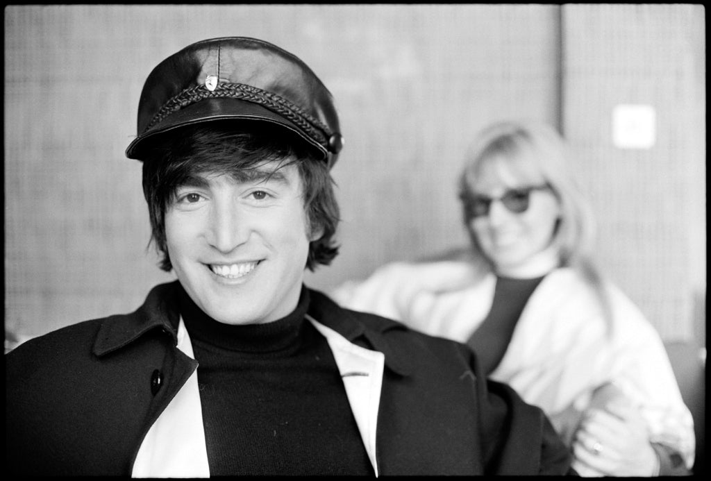 john lennon wears his leather cap, cynthia lennon is in the background